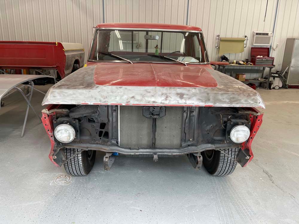 A red truck is sitting in a garage without a hood.