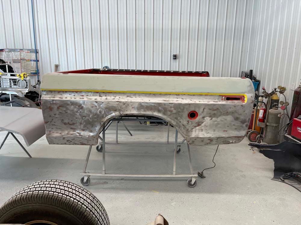 A truck bed is sitting on a cart in a garage.