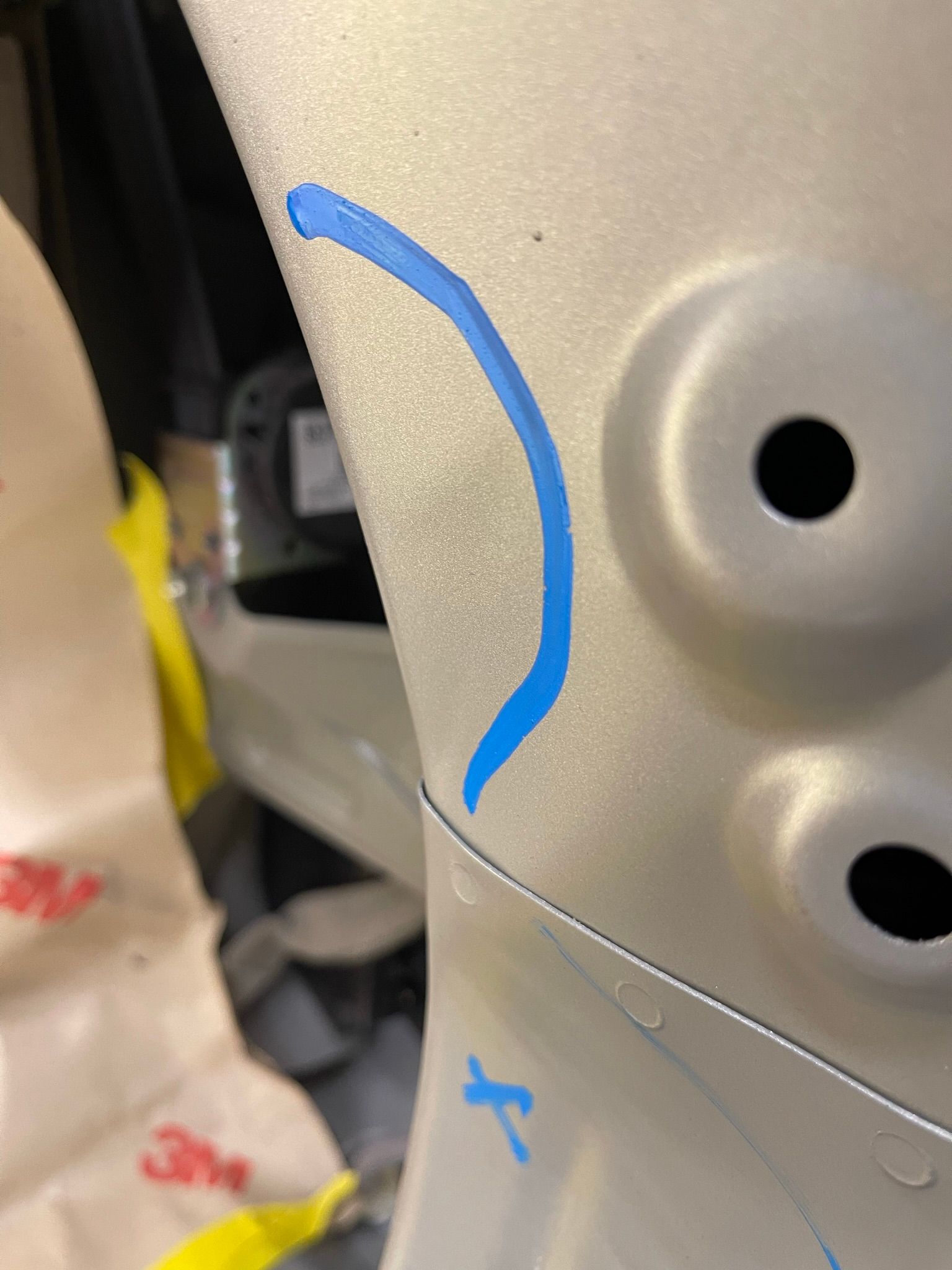 A close up of a piece of metal with a blue line drawn on it.