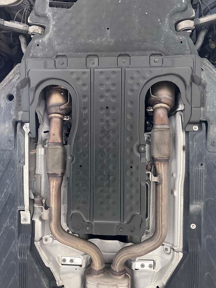 A close up of the underside of a car with exhaust pipes.