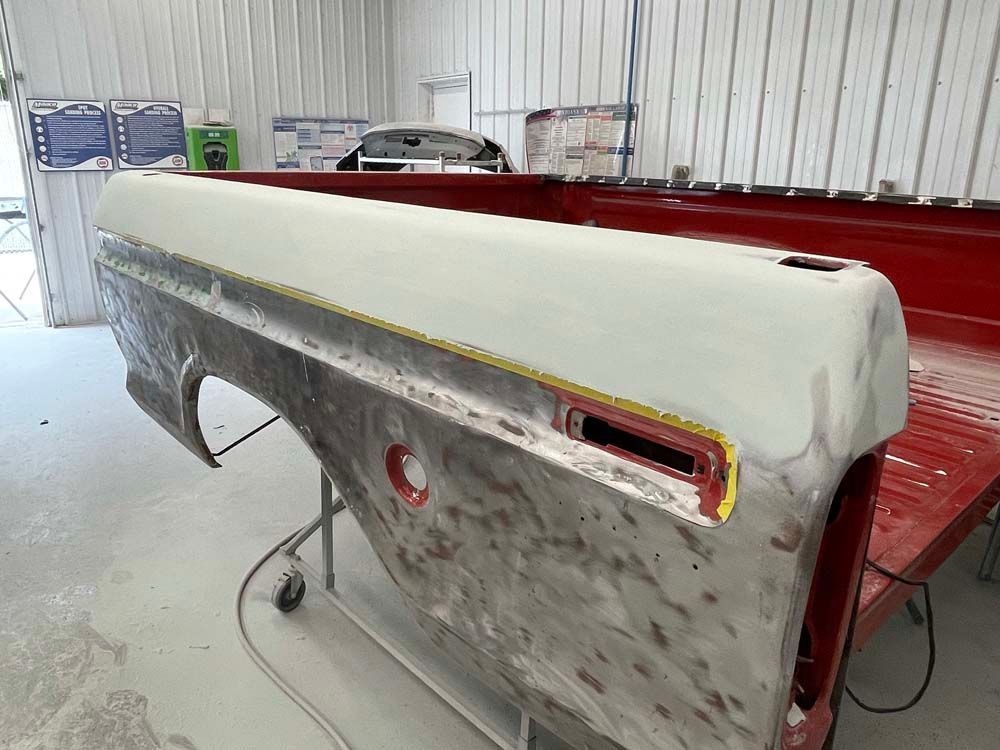 A truck bed is being painted in a garage.