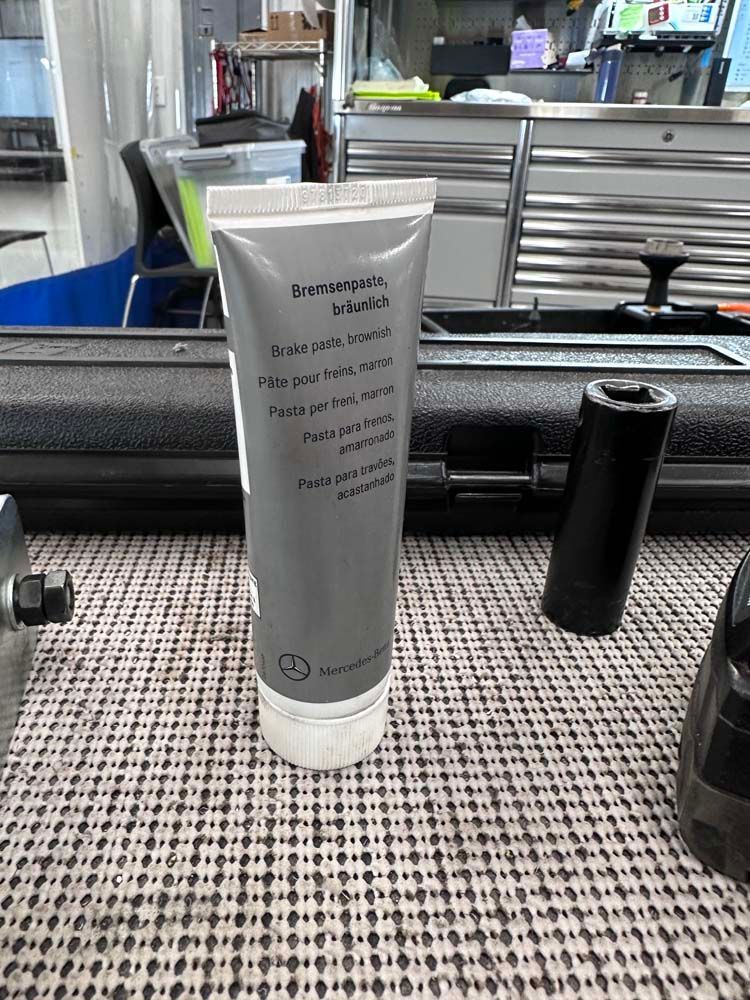 A tube of grease is sitting on a table next to a toolbox.