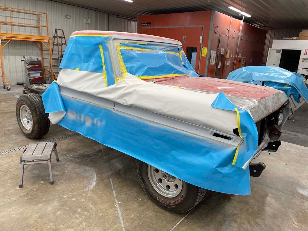 A truck is covered in blue tape in a garage.
