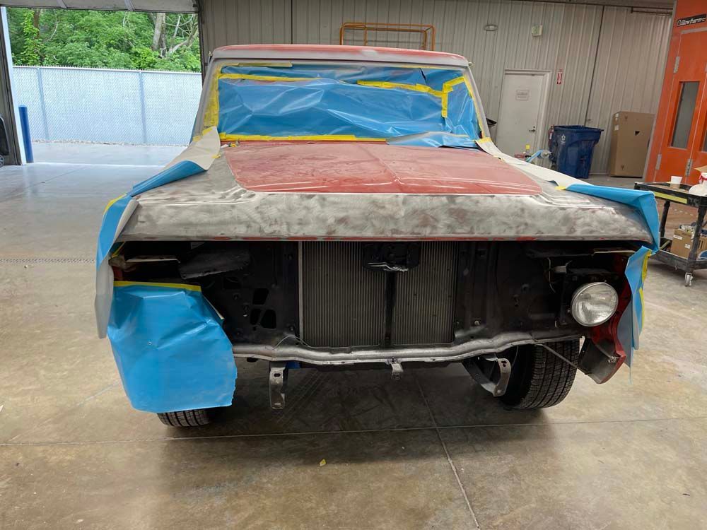 A truck is sitting in a garage covered in blue tape.