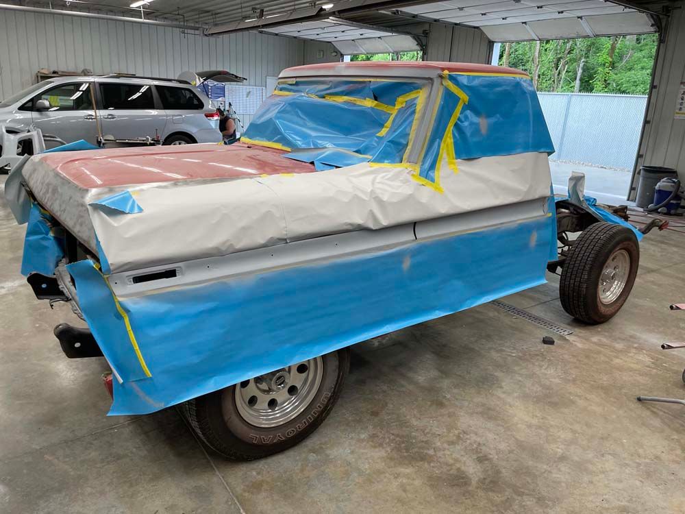 A truck is covered in blue tape in a garage.