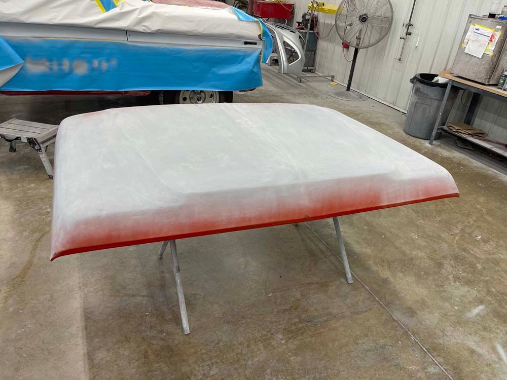A roof is being painted in a garage with a fan in the background