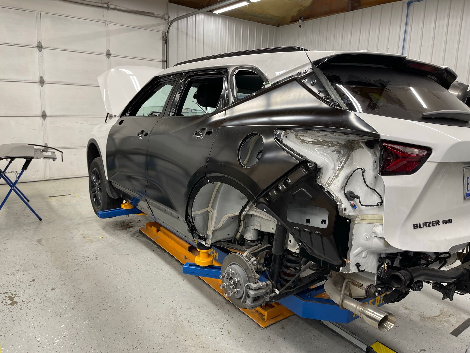 A car that has been damaged is sitting on a lift in a garage.