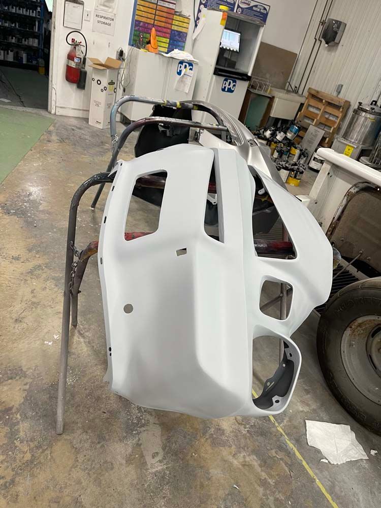 A white bumper is sitting on a metal stand in a garage.