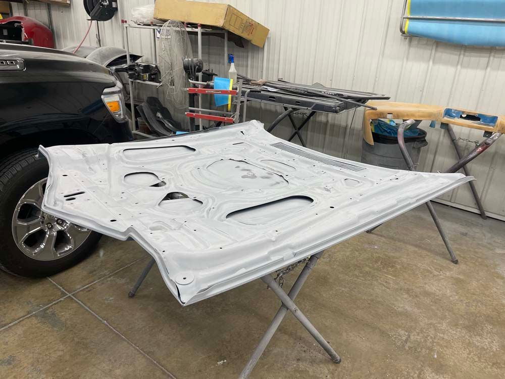 The hood of a car is sitting on a table in a garage.