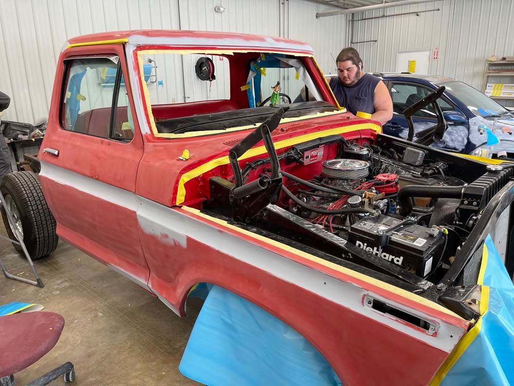 A man is working on a red truck in a garage.