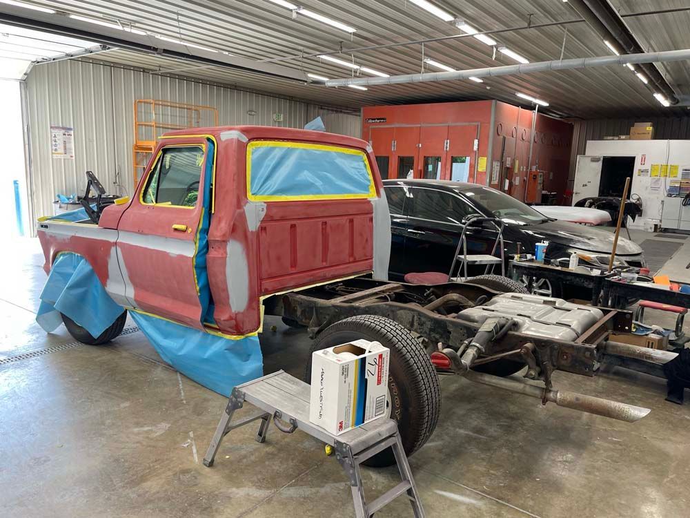 A red truck is being painted in a garage.