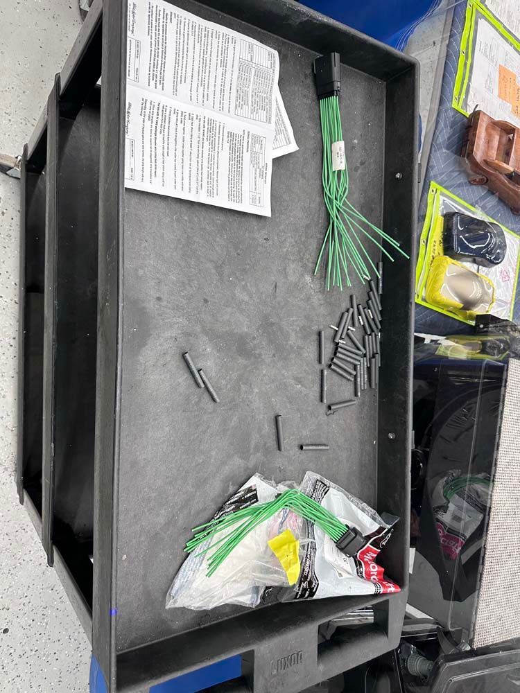 A black tray filled with lots of tools and wires.