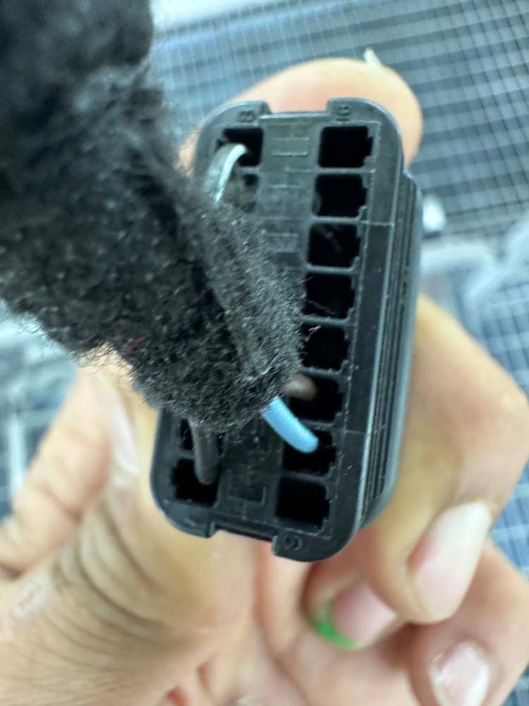 A person is holding a black connector in their hand.