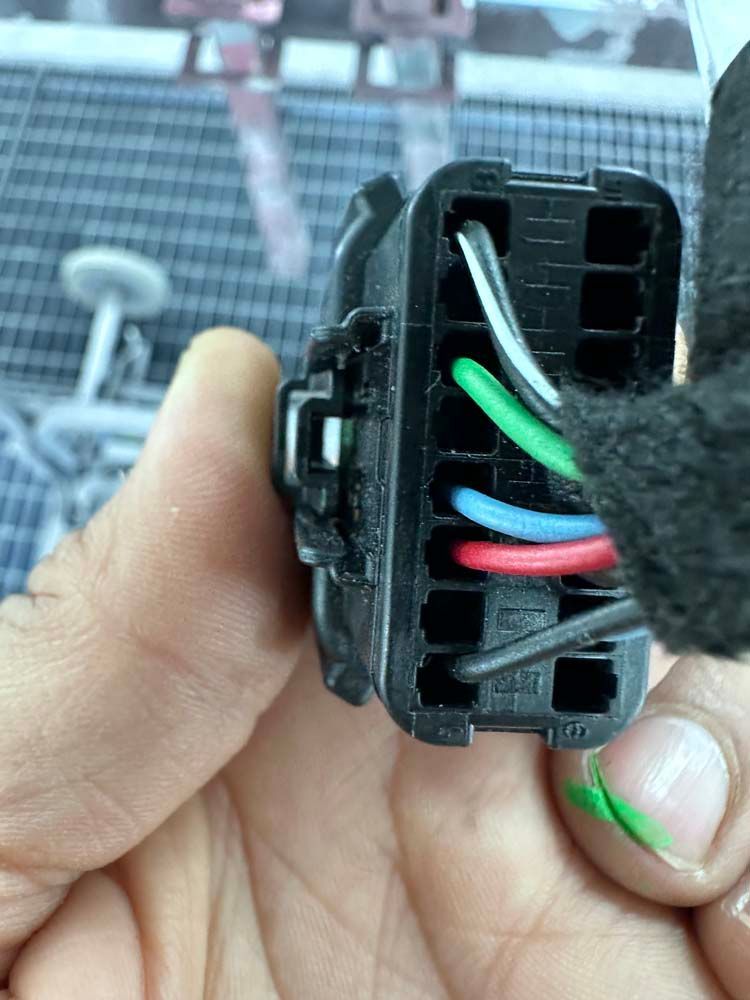 A person is holding a connector with wires coming out of it.