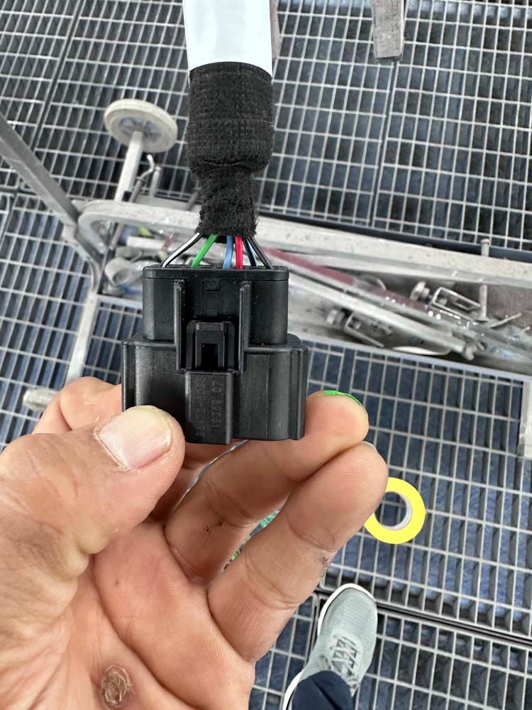 A person is holding a black connector in their hand.