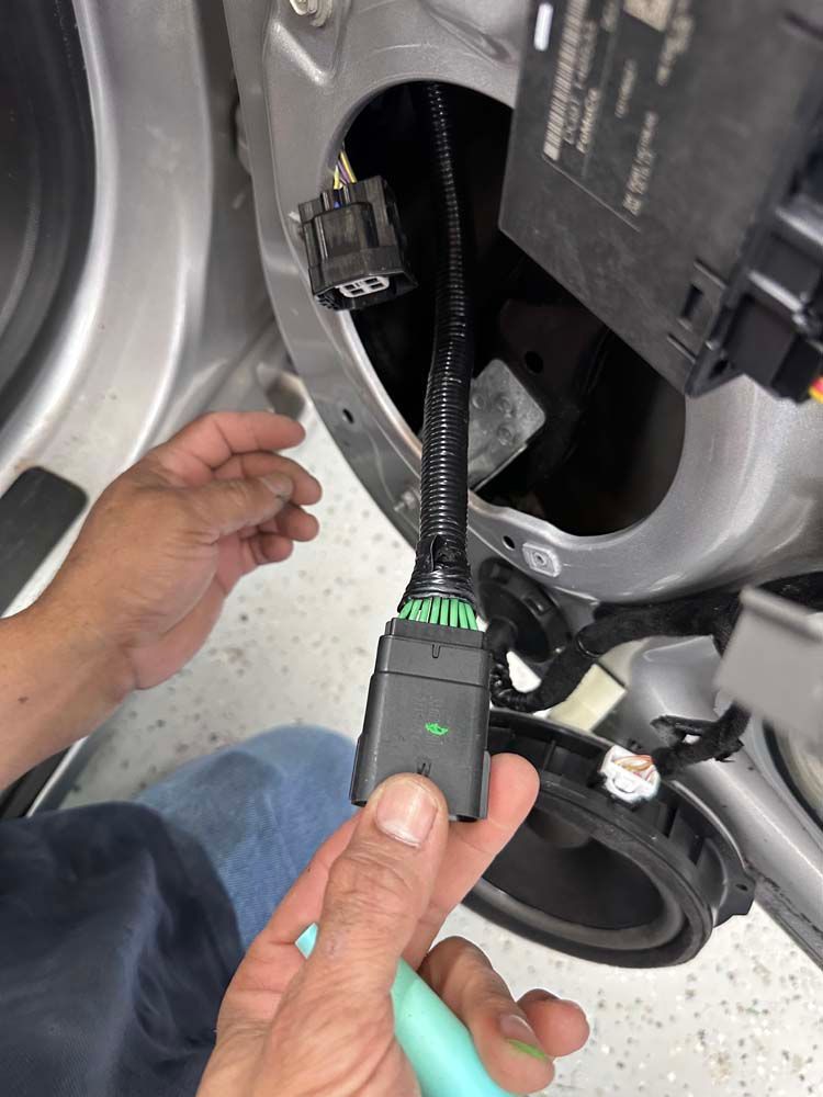 A person is holding a plug in their hand in front of a car door.
