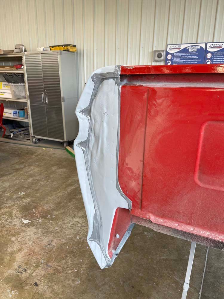 A red truck is being painted in a garage.