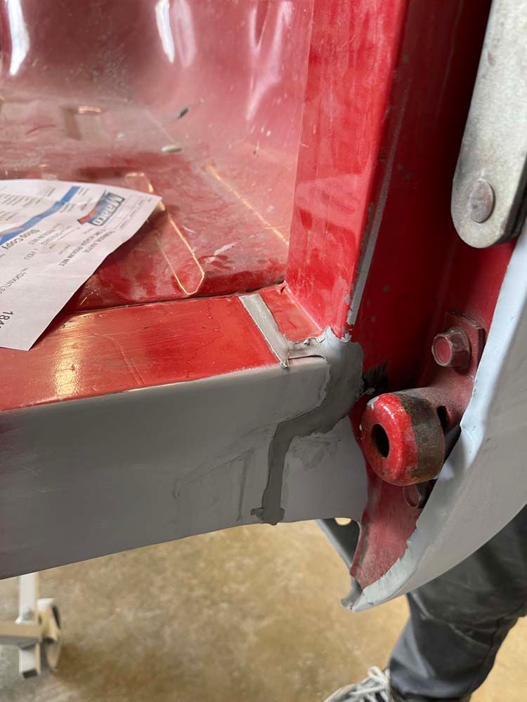 A person is standing next to a red piece of metal.