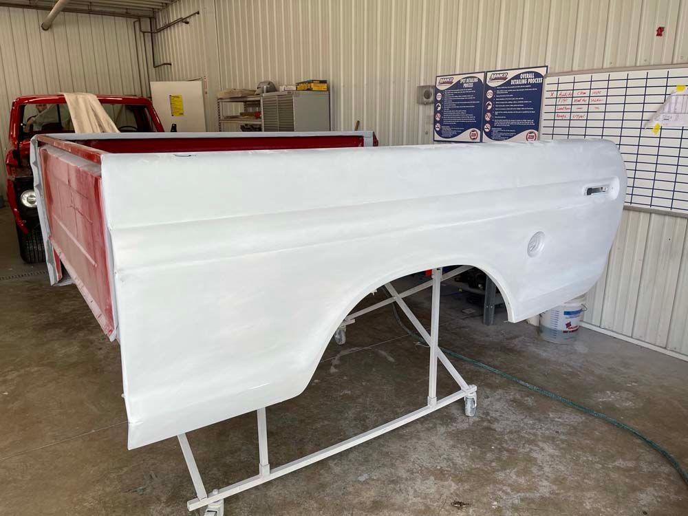 A white truck bed is sitting on a white stand in a garage.