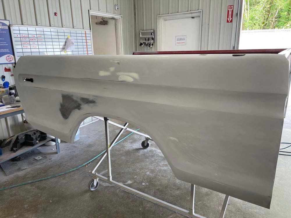 A truck door is sitting on a stand in a garage.