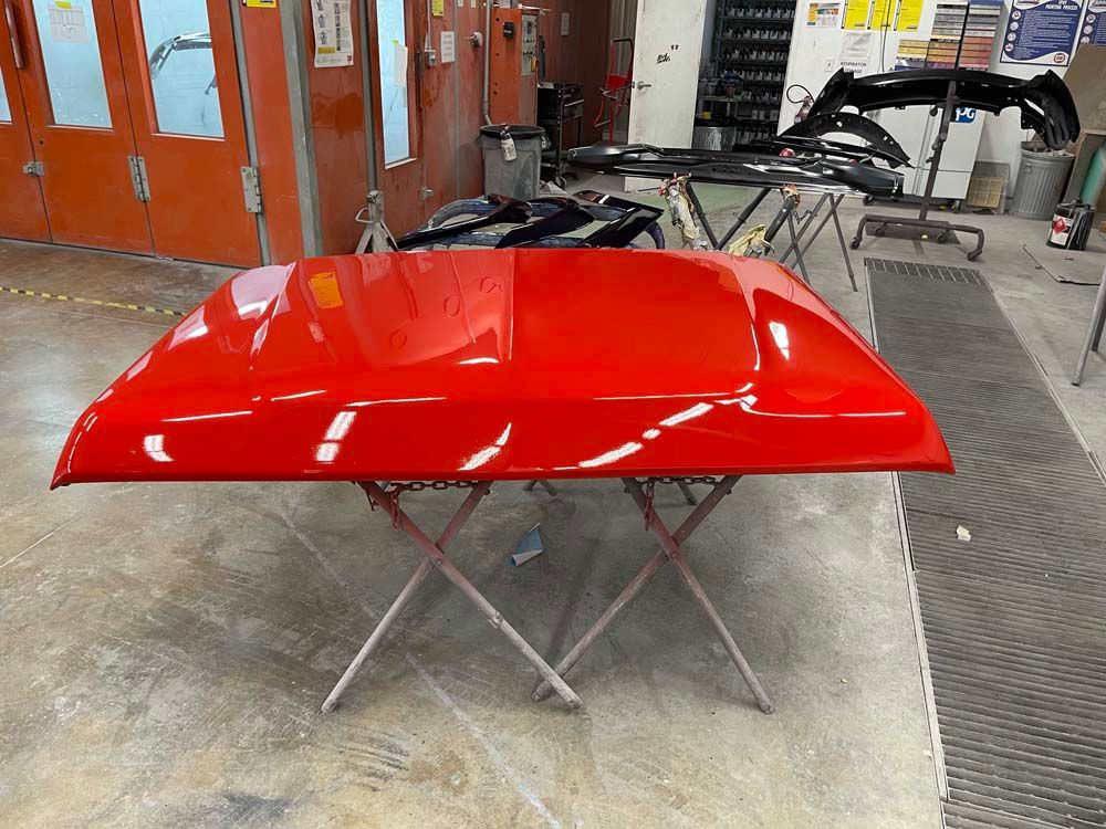 A red hood is sitting on a table in a garage.