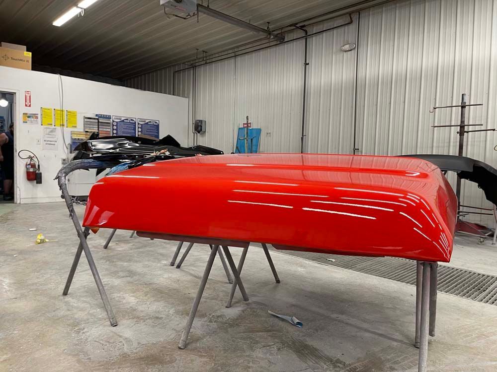 A red canoe is sitting on a table in a garage.
