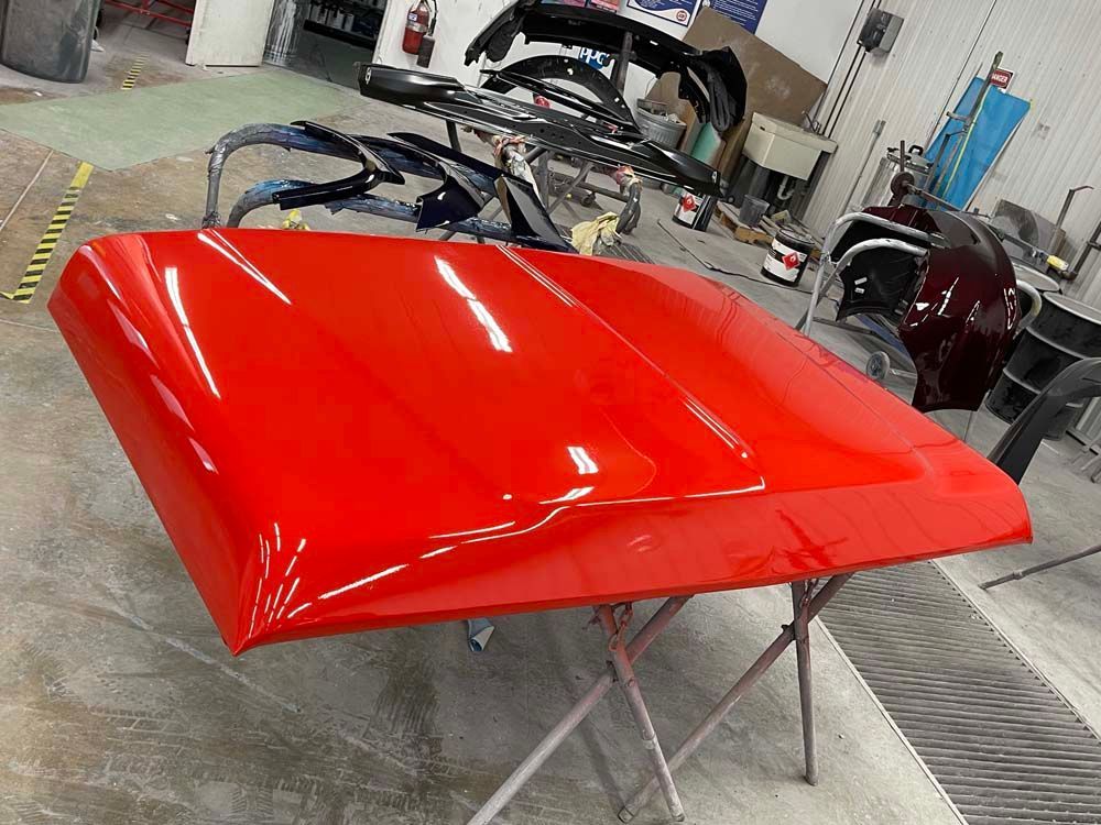 A red hood is sitting on a table in a garage.