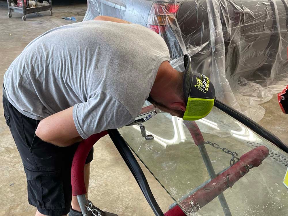 A man is bending over to look at a windshield.