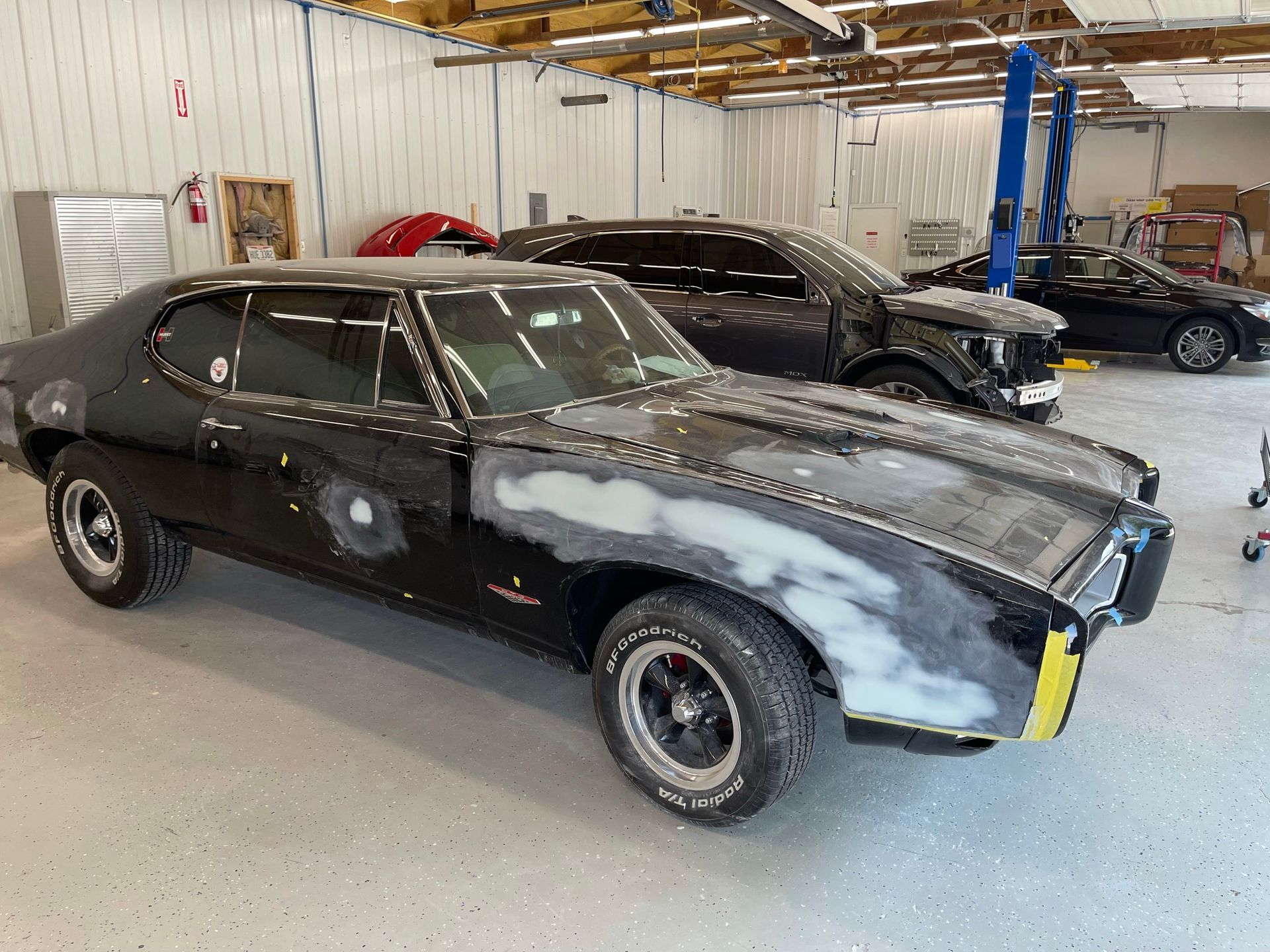 A black car is being restored in a garage.