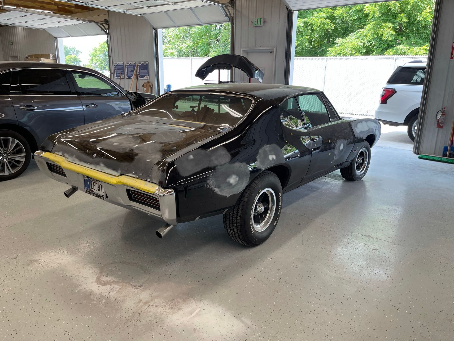 A black car is parked in a garage with the hood up.