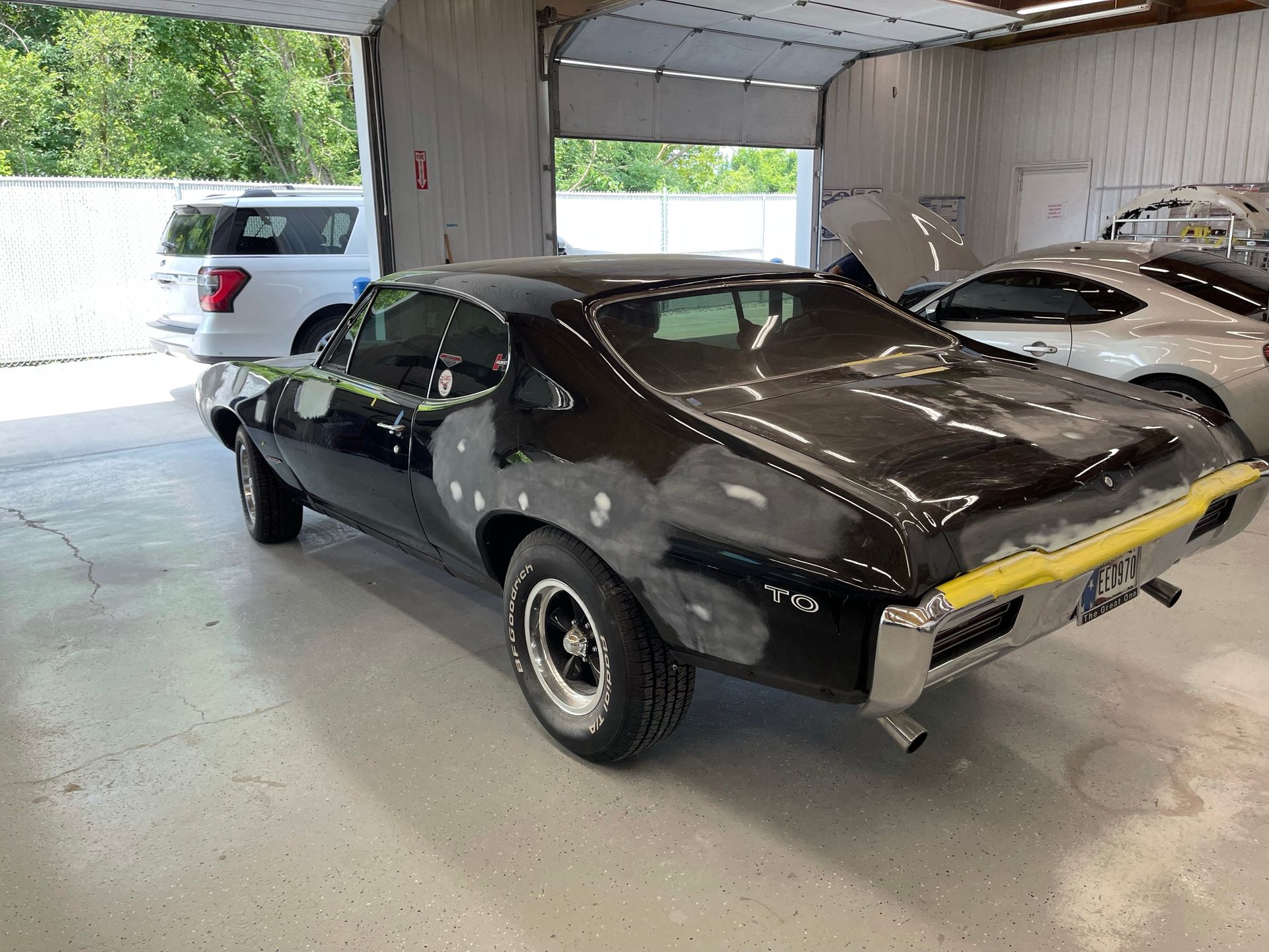 A black car is being restored in a garage.