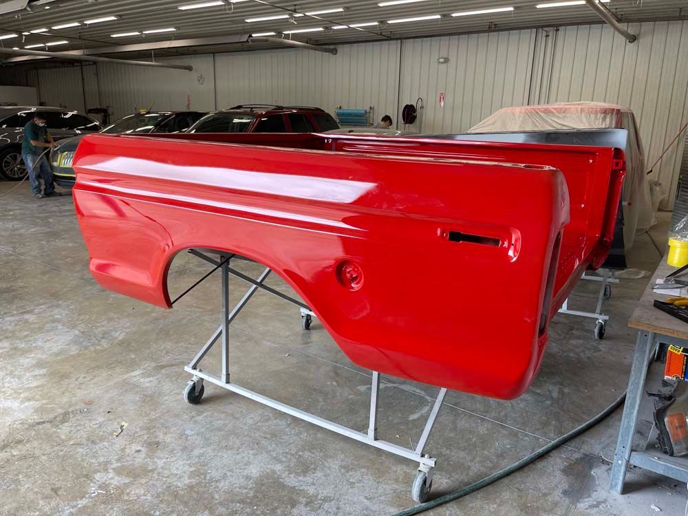 A red truck bed is sitting on a stand in a garage.