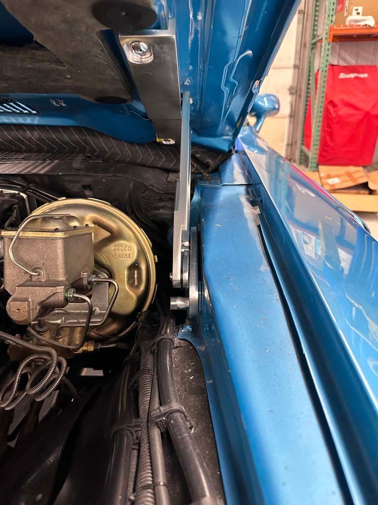 A close up of a blue car with the hood open.