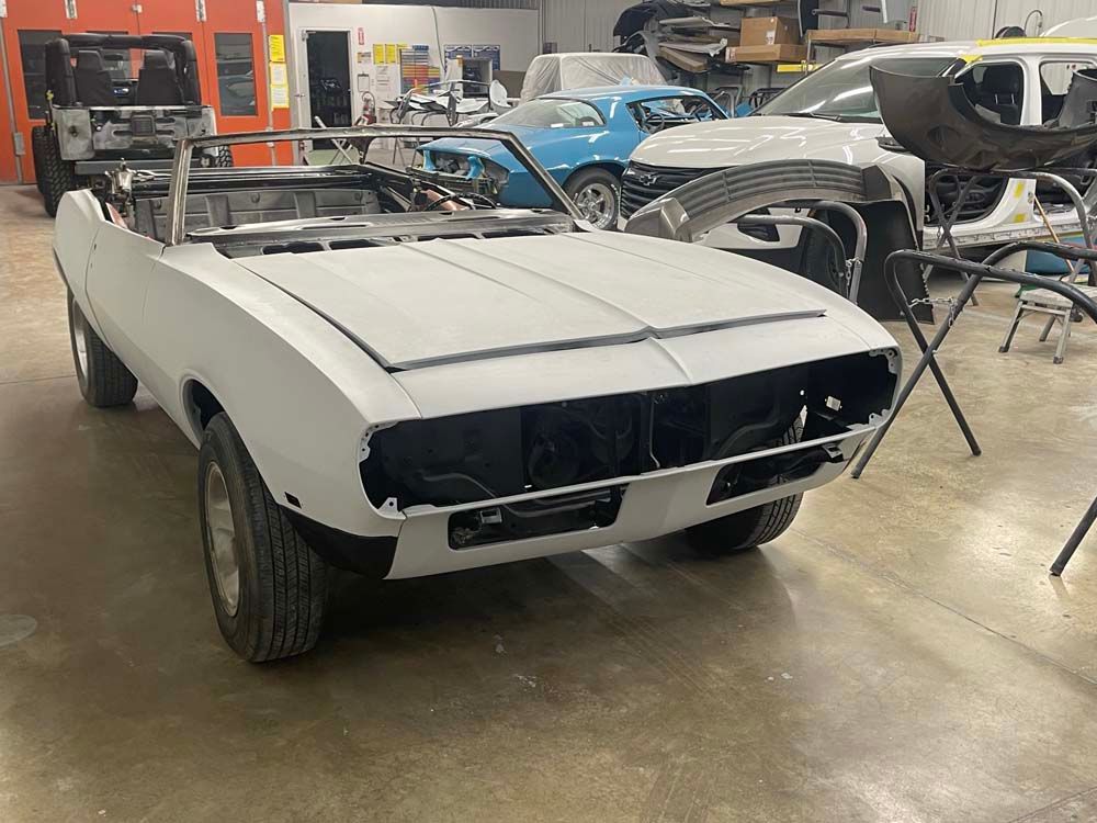 A white car is being built in a garage.