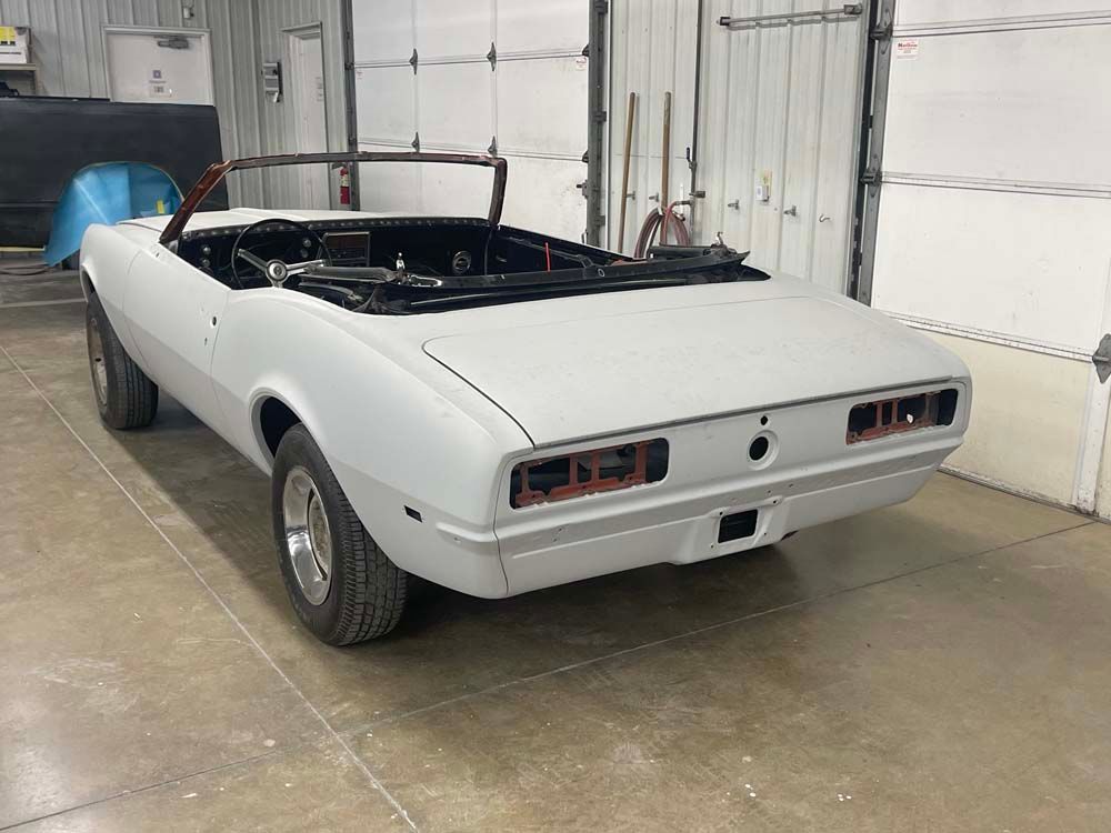 A white convertible car is parked in a garage.