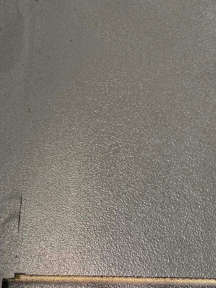 A close up of a gray tile floor with a wooden border.