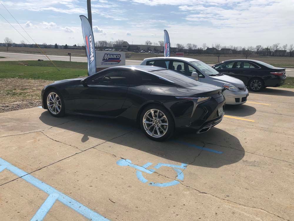 A black sports car is parked in a handicapped parking spot.