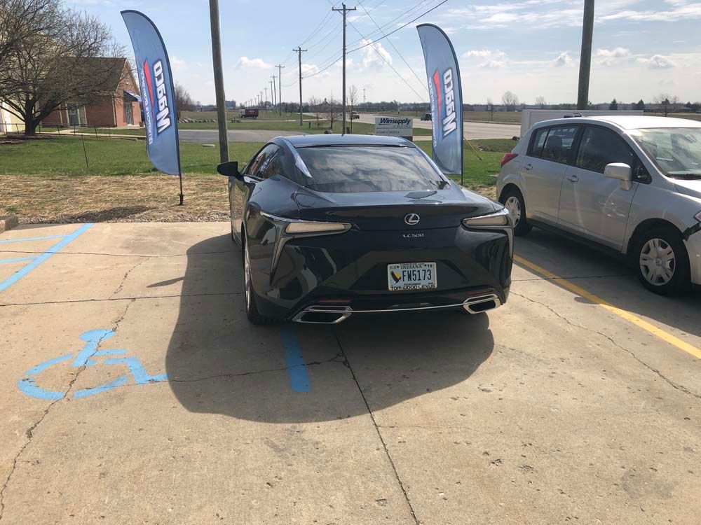 A black sports car is parked in a handicapped parking spot.