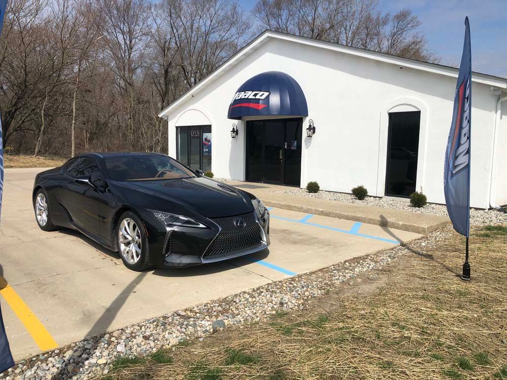 A black sports car is parked in front of a white building.