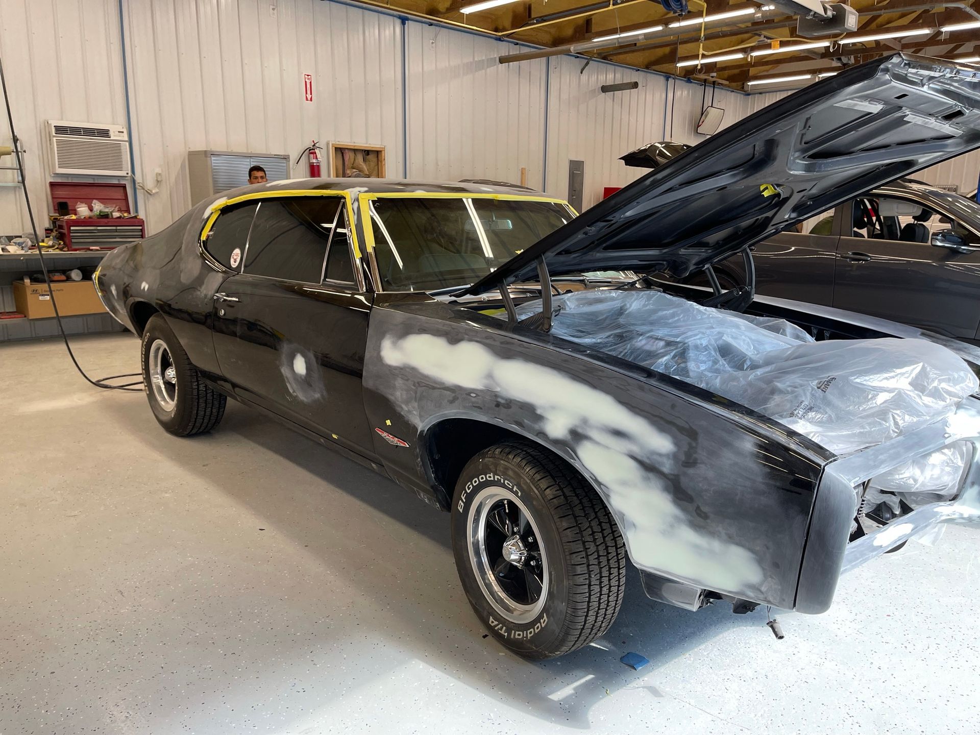 A black car with the hood up in a garage