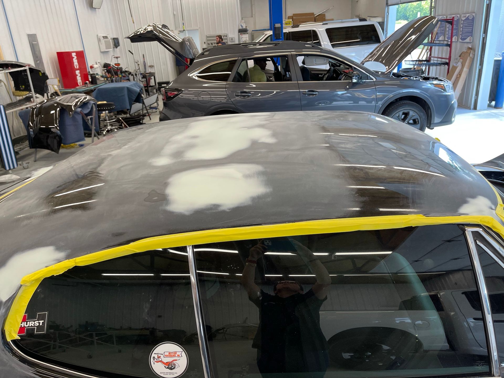 The roof of a car is being painted in a garage.