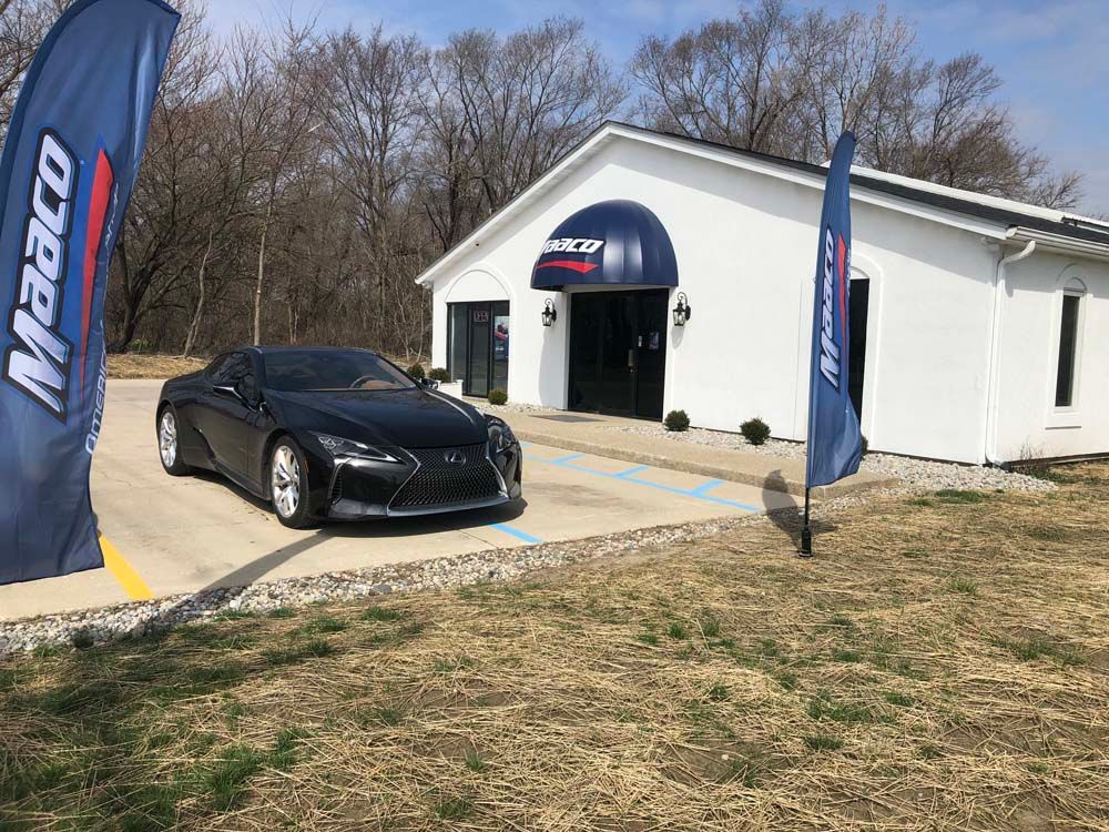 A black sports car is parked in front of a white building.