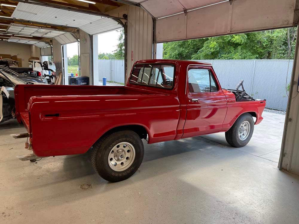 A red truck is parked in a garage with the door open.