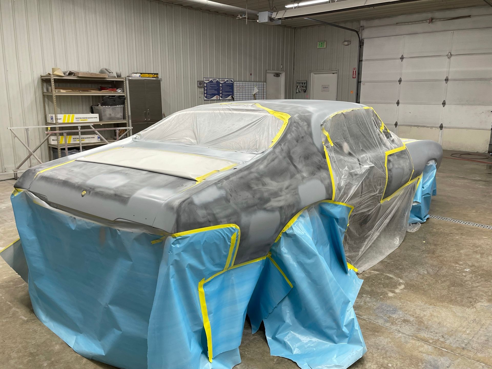 A car is covered in plastic in a garage.