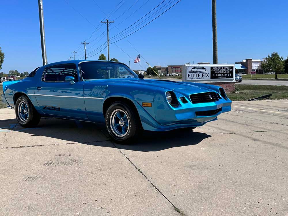 A blue car is parked on the side of the road.