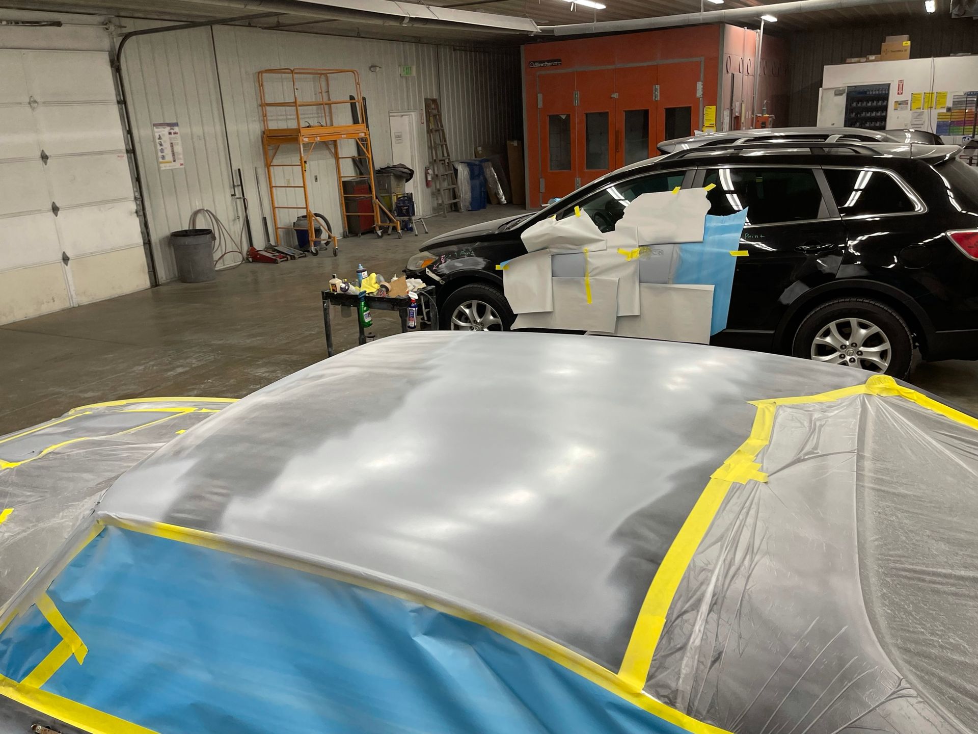 A car is being painted in a garage.