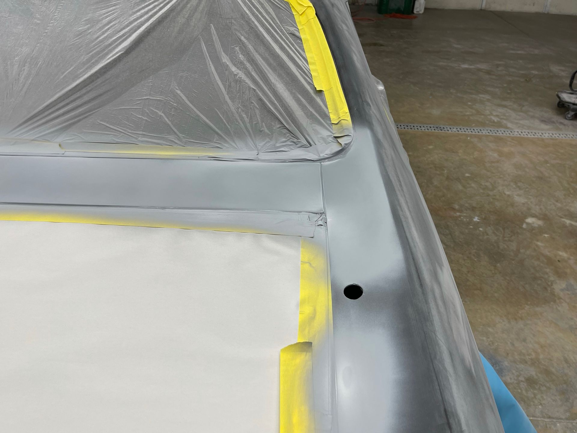 A car is being painted in a garage with yellow tape.