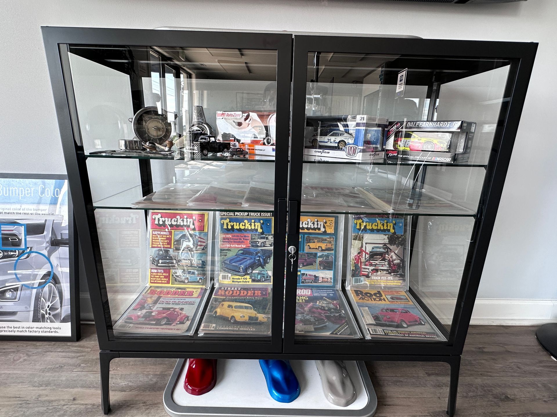 A glass display case filled with magazines and toys in a living room.