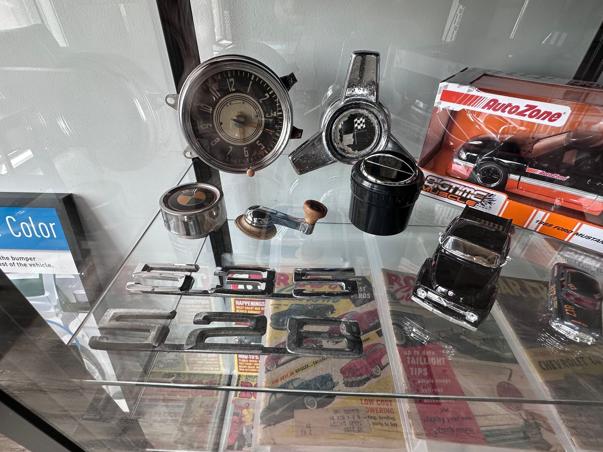 A display case filled with a variety of car parts and a toy car.
