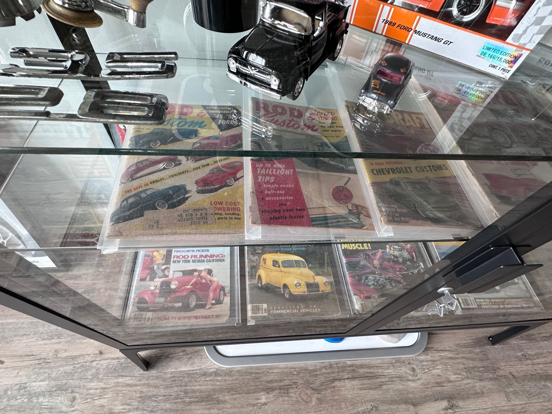 A glass display case filled with books and toy cars.